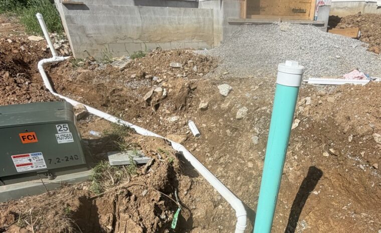 o Image 1 (Trench line perspective): A long, deep dirt trench between two under-construction homes showcasing a newly installed white PVC sewer pipe running towards the main hookup