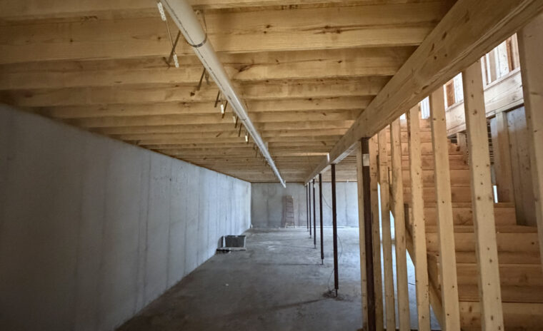 Long main PVC waste line running along basement ceiling joists toward main sewer stack.