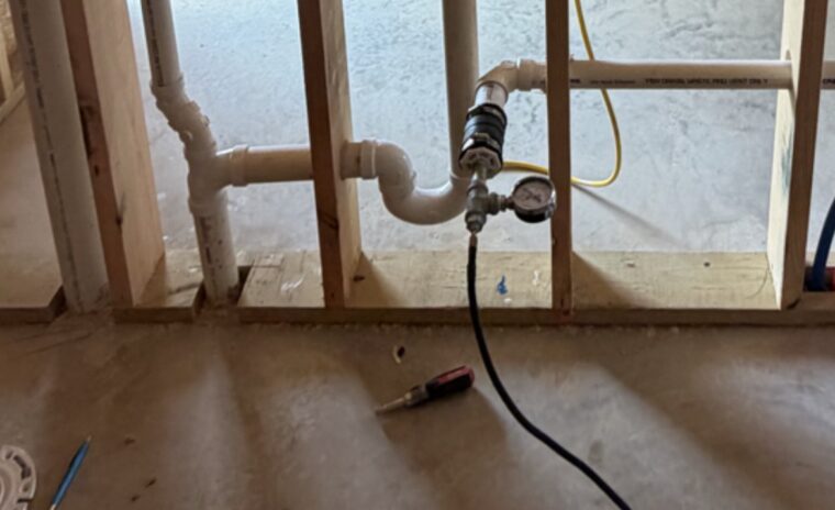Laundry box rough-in connected to a test gauge assembly and Milwaukee inflator during a DWV pressure test.