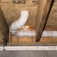 Overhead perspective showing neat PVC drain branches and strap hangers under crawlspace subfloor.