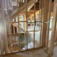 Wood-framed multi-story home under construction showing PVC drain and vent stack rough-in piping running through wall studs between floor levels.