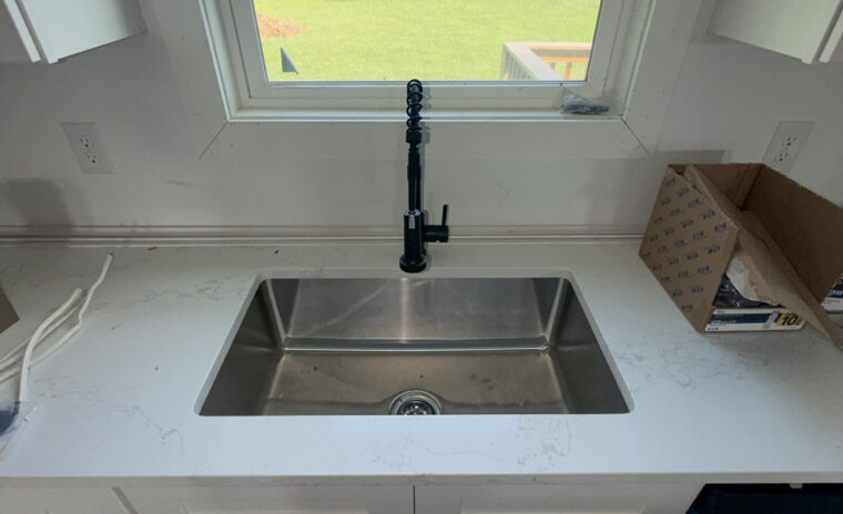 Undermount single-basin stainless steel kitchen sink with high-arc matte black pull-down faucet.