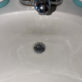 Newly installed chrome grid strainer drain body mounted in white porcelain sink basin.