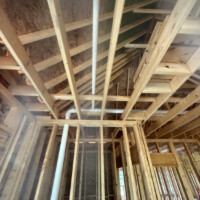 40EDDF8D 2DCC 4DEC 897A 20A7B7511E3B f71f539c fa04 4f25 9c65 6ec0644efcc3 A vertical white PVC plumbing stack centered perfectly inside an open two-by-four wood stud partition wall inside a rough-in home.