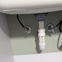 585743CE ADC6 4F6F 829C 69B64579B7F3 58e4cbdf 1aa4 4e2f b970 e00f7be57af4 (1) 1. Professional under-sink plumbing with white PVC P-trap and chrome shut-off valves.