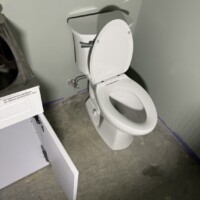 8A071319 EA7C 49EA AF18 CA06D410C0AB f6e173d1 01e0 4af6 a7af af684aad865e 2. Securely installed white porcelain toilet on a garage concrete floor