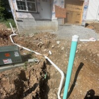 8E21FB5E CCFA 4A50 8DF4 FC024C37B137 7063d389 bce9 4297 b48e 7043d8b41209 o Image 1 (Trench line perspective): A long, deep dirt trench between two under-construction homes showcasing a newly installed white PVC sewer pipe running towards the main hookup