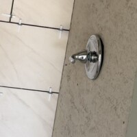CD226703 46CF 44B1 99F1 486D7337F6E8 3896674c 64e4 4baa b43d 30145aabf994 3. Brushed nickel shower valve against large-format marble-style wall tile