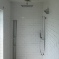 D2AD6715 744F 4B75 AD65 17E0C52CD92B 90ff21c6 91c5 497d 9773 a2b1ad849ccf A modern walk-in shower featuring white subway tile, a ceiling-mounted square chrome rain shower head, and a wall-mounted hand-held sprayer attachment.