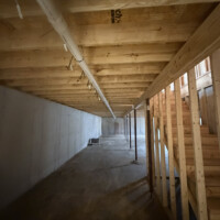 DF880E62 B48B 4CD2 8E77 FE3AC18A0B9B 0409b3a9 8f64 4c18 88e4 352f23094278 Long main PVC waste line running along basement ceiling joists toward main sewer stack.