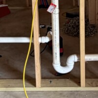 IMG 1813 In-wall laundry standpipe and P-trap with a yellow test plug inflation hose extending to the floor.