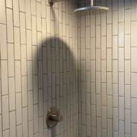 ReactNativeBlobUtilTmp iq3pjdjbmsbt6qoen1svxl Modern rainfall showerhead and mixing valve professionally installed against a vertical white subway tile shower wall.
