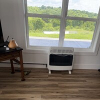 ReactNativeBlobUtilTmp mivh8xwdtlk98tz2nzqyf9 White wall heater installed under a large window with black iron piping running along the baseboard.