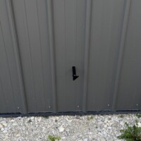 ReactNativeBlobUtilTmp q784igcy8tvzu5v9q6y4 Exterior 1/2-inch gas line stub-out on gray metal siding showing the 18-inch clearance above the gravel and dirt ground.