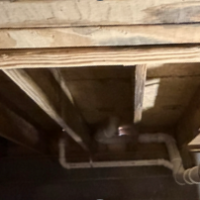 Screenshot 2026 07 25 070600 Plumbing technician adjusting under-floor drain line fittings during a crawlspace rough-in in Crab Orchard, KY.