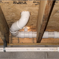 Screenshot 2026 07 25 074623 Overhead perspective showing neat PVC drain branches and strap hangers under crawlspace subfloor.