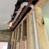 ReactNativeBlobUtilTmp 0v3xv4b1ct3qxqvq6uocyu PVC drain waste and vent pipe running above framed wall through opened ceiling framing in a whole-house historic renovation.
