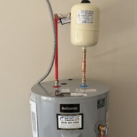 ReactNativeBlobUtilTmp 3187bvaom4wu0hlas710tb Reliance electric water heater installation featuring an overhead thermal expansion tank and PEX supply connections