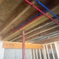 ReactNativeBlobUtilTmp 31num1b6mcyykrzfzza9oe PEX water lines neatly routed through open wall studs and overhead ceiling joists alongside sheet metal ducting.