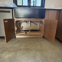ReactNativeBlobUtilTmp 7gjefkr7eiirbh1xn656e Apron-front farm sink installation showing PEX lines, tailpiece drain, and dishwasher discharge hose connection.