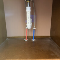 ReactNativeBlobUtilTmp 8aawtrda74o8t88c7c4jl8 Neat bathroom sink cabinet interior showing red and blue PEX supply lines, shutoff valves, and PVC P-trap assembly.