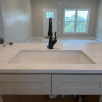 ReactNativeBlobUtilTmp 8dm6ljniddwdyq97e3eu White undermount kitchen sink with a modern matte black pull-down faucet on quartz countertops.