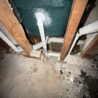 ReactNativeBlobUtilTmp 8dtyv17ct14xsa87m8e2il Underground PVC drain line installation with jackhammered concrete subfloor exposed near vintage green tub.