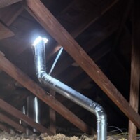 ReactNativeBlobUtilTmp 9odzb8y1debxarqpfjinc (1) B-vent metal chimney pipe angled through attic framing with proper clearances and metal bracing.