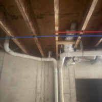 ReactNativeBlobUtilTmp eh0wmq1597m4qql31c00pm Vertical PVC drain stack and red PEX supply tubing routed past flexible HVAC ductwork in Bardstown, KY.