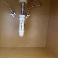 ReactNativeBlobUtilTmp h3xa1m8iprbinxpb5g624 Under-sink vanity drain connections and chrome angle stops inside a custom vanity cabinet.