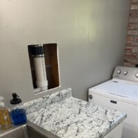 ReactNativeBlobUtilTmp hkk67nw252pb6s4aeuo1zo Completed wall repair section above granite countertop adjacent to laundry room washing machine.