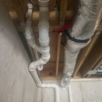 ReactNativeBlobUtilTmp hs39qylhb5mtbzxgk2cma Vertical PVC drain stack and red PEX supply tubing routed past flexible HVAC ductwork in Bardstown, KY.