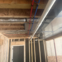 ReactNativeBlobUtilTmp j8at7c8asekwgivkmx9bc Horizontal 3-inch PVC drain pipe and red and blue PEX water lines running parallel to metal HVAC trunking.
