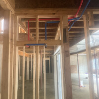 ReactNativeBlobUtilTmp kgkpy0uve1d2oeiqqi33v Horizontal 3-inch PVC drain pipe and red and blue PEX water lines running parallel to metal HVAC trunking.