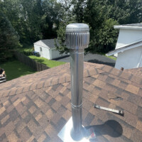 ReactNativeBlobUtilTmp mcu65sy3syb4z0garu2aq Galvanized double-wall metal B-vent pipe terminating through roof shingles with weather cap and flashing.