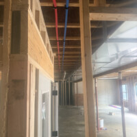 ReactNativeBlobUtilTmp mgeeu5n5z8o5y687n2tncn Horizontal 3-inch PVC drain pipe and red and blue PEX water lines running parallel to metal HVAC trunking.