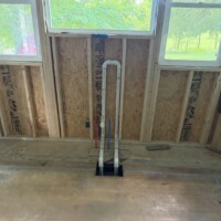 ReactNativeBlobUtilTmp tipq8y051gi1pzptzxqhth Loop vent PVC piping routed under window framing during whole-home rough-in plumbing stage.