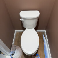 ReactNativeBlobUtilTmp vi8vpnkti2os08w0wphgyj Newly installed white Gerber toilet in a finished bathroom with protective floor paper.vi8vpnkti2os08w0wphgyj