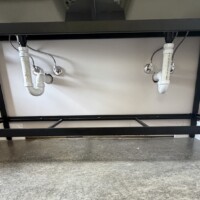 ReactNativeBlobUtilTmp zby6jn18tvpb9jbs2ejc Open-frame double vanity rough-in with twin P-traps, PVC drain lines, and dual shutoff valves.