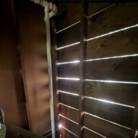 ReactNativeBlobUtilTmp zg5gigflm0mem02v52djor Vertical PVC pipe installation running past original redwood wall construction.