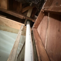 ReactNativeBlobUtilTmp zzhwzhly91qdjwwiphxkmp Close-up low-angle view of vertical Schedule 40 PVC stack piercing through original framing and plaster