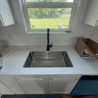 ReactNativeBlobUtilTmp 15665jlofjxvq422jqyhi Undermount single-basin stainless steel kitchen sink with high-arc matte black pull-down faucet.
