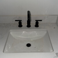 ReactNativeBlobUtilTmp cs86d0o024qdotmq6l3aut Modern matte black wide-spread bathroom faucet mounted on white quartz countertop.