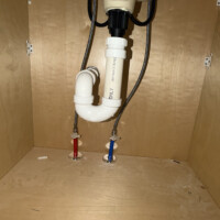 ReactNativeBlobUtilTmp ftufmgq4vffmclignh3wxl Under-sink plumbing cabinet setup featuring PVC P-trap assembly and color-coded PEX water supply lines with shutoff valves.