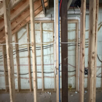 ReactNativeBlobUtilTmp tnncljxp422wo9233rjbj Looking up through open floor joists showing black iron gas lines, PEX water lines, and PVC drain pipes strapped to framing.