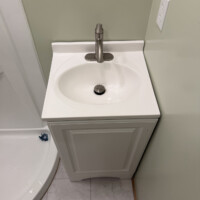 ReactNativeBlobUtilTmp 5amghnzthsox2sypoltbra Top-down view of a modern white vanity sink with brushed nickel faucet hardware.