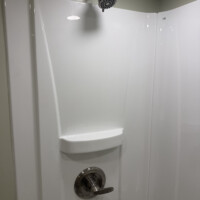 ReactNativeBlobUtilTmp acdhu3bhc8qaar90qgkzgp Single-handle brushed nickel faucet mounted on a white vanity top next to a modern stall shower.