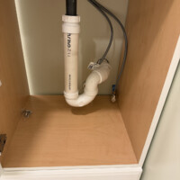 ReactNativeBlobUtilTmp aidrgh3swcld536rkn5w8d Clean under-sink drain assembly featuring a PVC P-trap and flexible water supply lines inside a vanity.